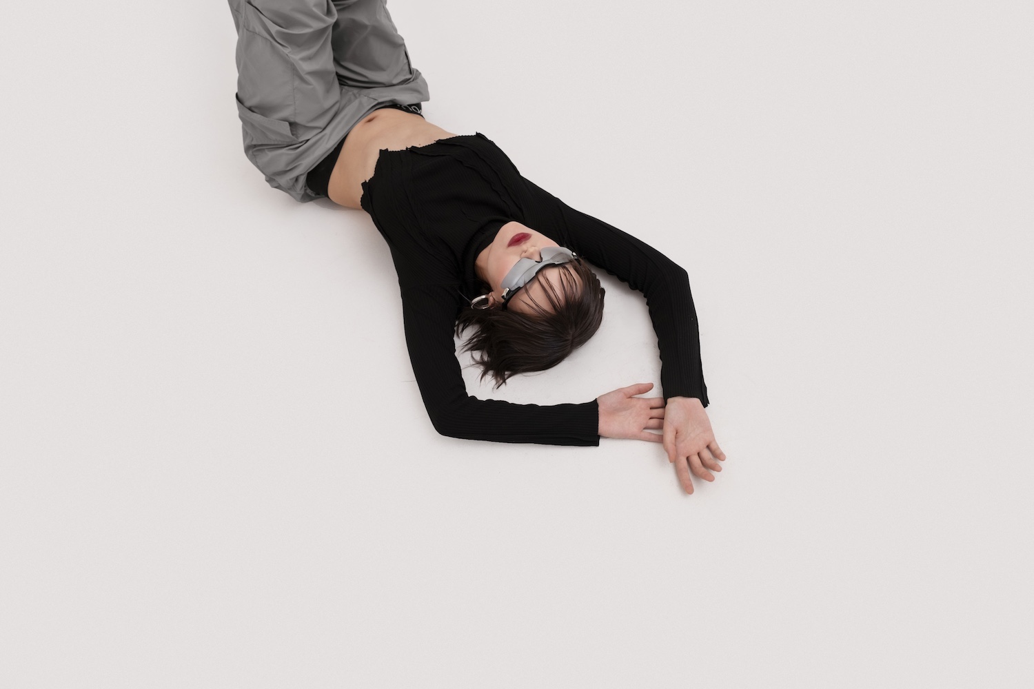 Frau in futuristischer Sonnenbrille liegt auf weißem Boden