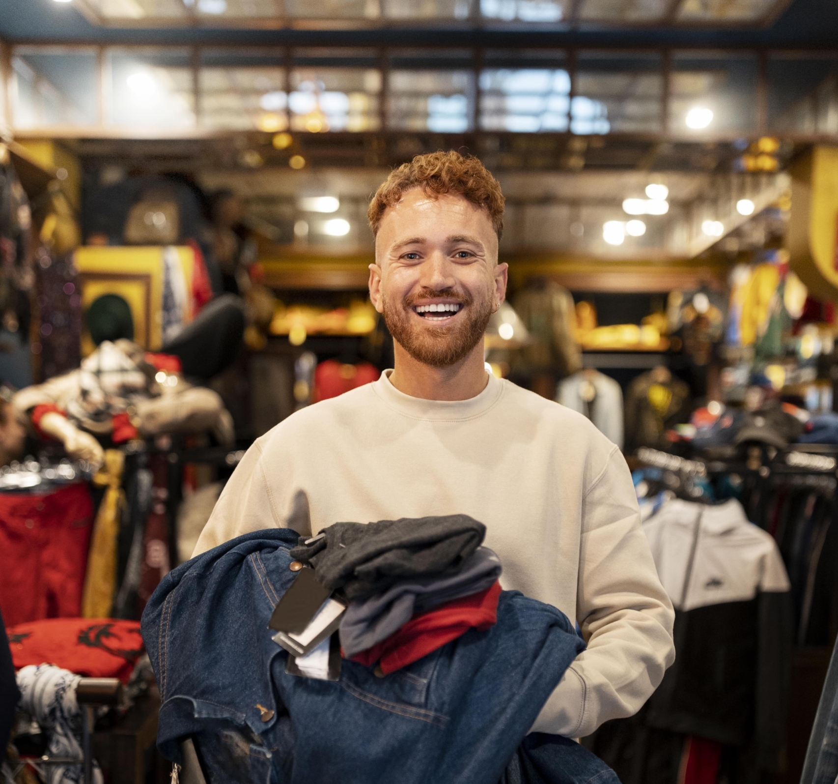 Lachender Mann mit Kleidung in Boutique